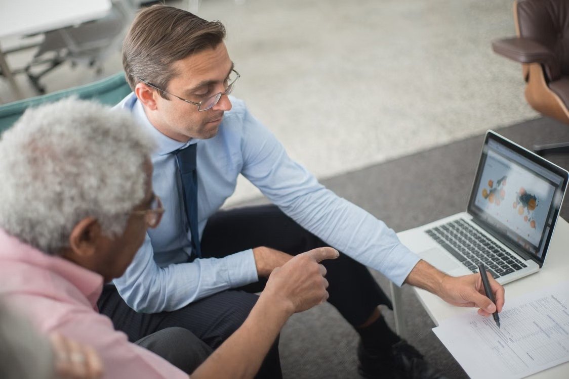 Professionals reviewing financial documents and laptop reports during a consultation.